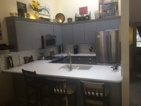 Renovated kitchen with gray cabinets, white counters and subway tile backsplash